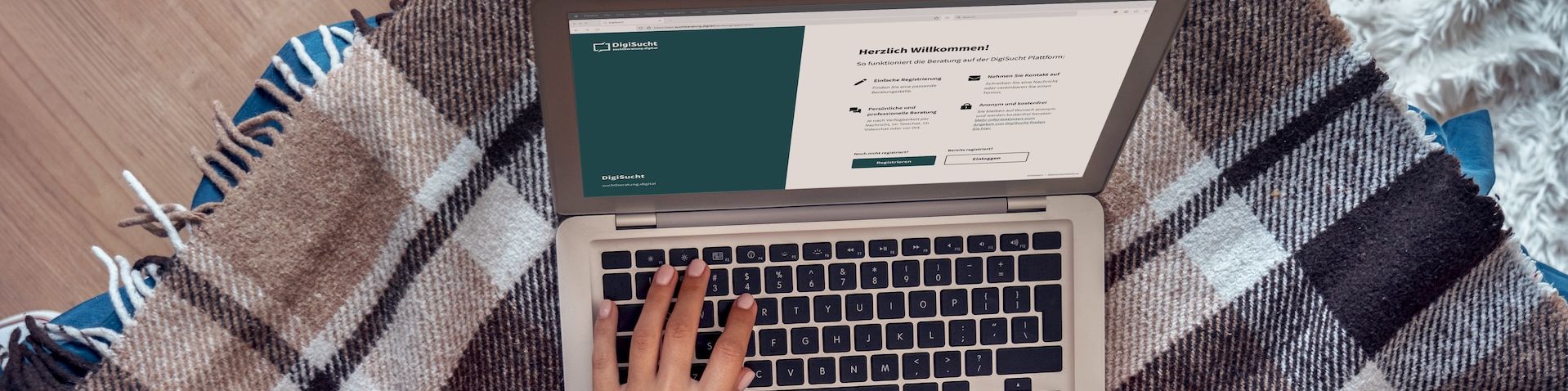 Eine Person liegt mit Laptop auf einer Decke. Auf dem Bildschirm ist die DigiSucht Seite geöfnet.
