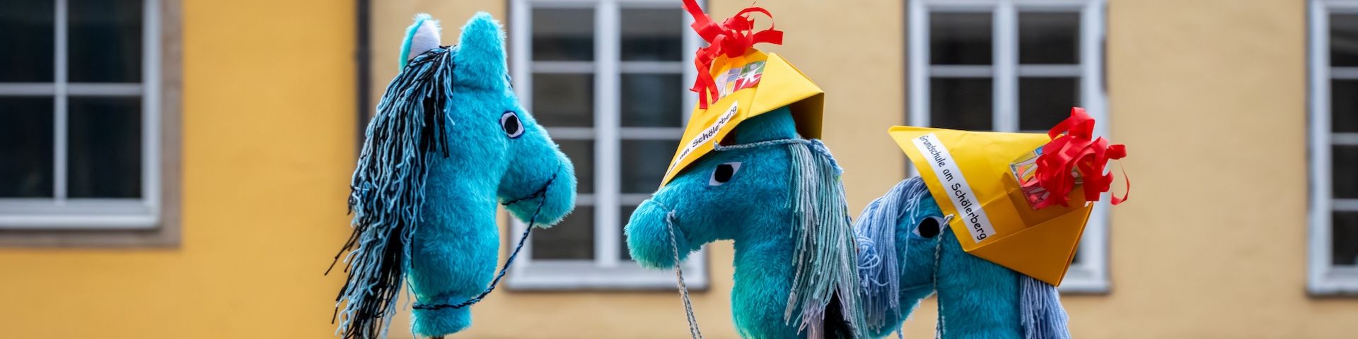 Blaue Steckenpferde mit gelben Papierhüten.